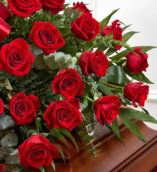 Half casket crafted with over 50 premium red roses, fresh greenery, and accented with a red satin ribbon