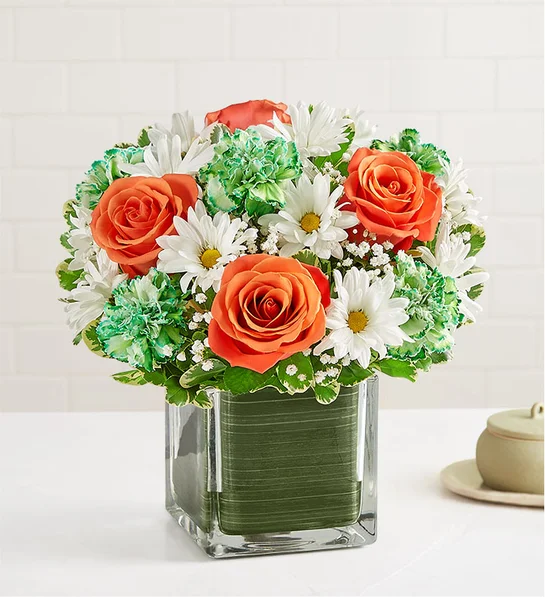 Arrangement with orange roses, dyed green carnations, and white daisy poms